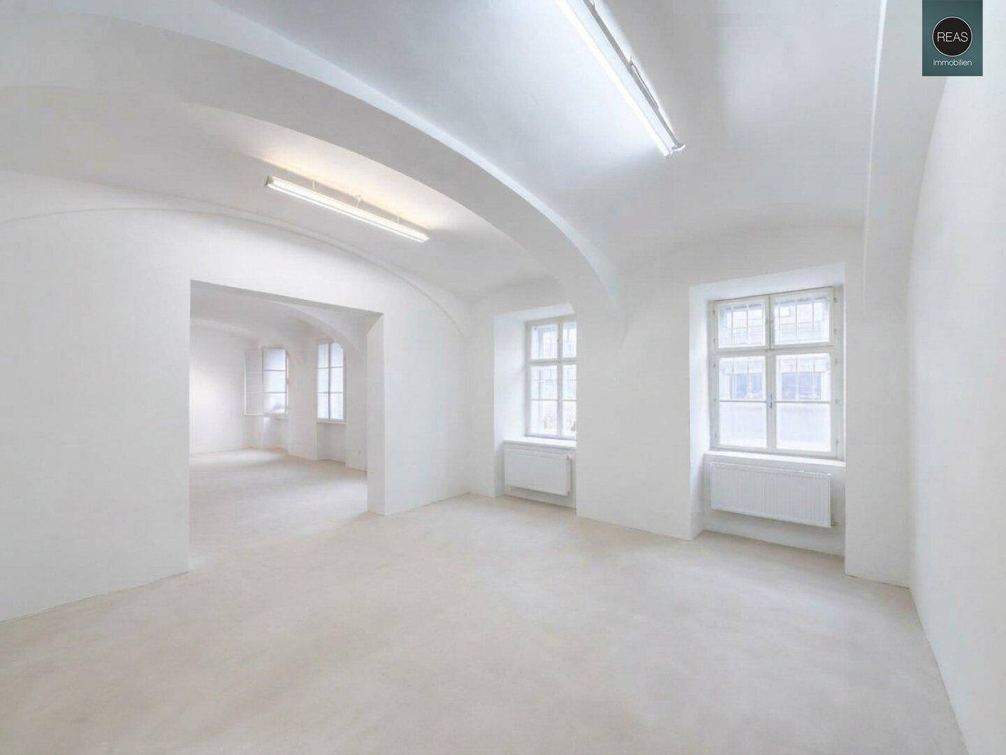 Geräumiger, weiß gestrichener Innenraum mit gewölbter Decke und mehreren Fenstern.