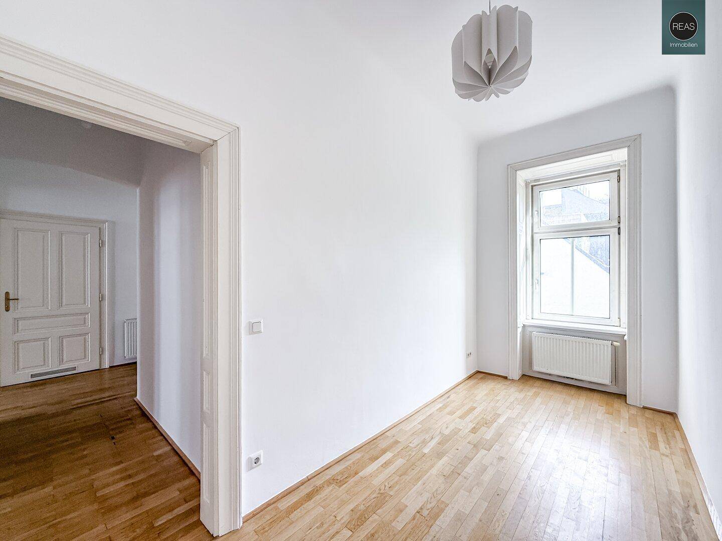 Ruhiges Zimmer mit Holzboden und einem Fenster, ideal als Schlaf- oder Arbeitszimmer.