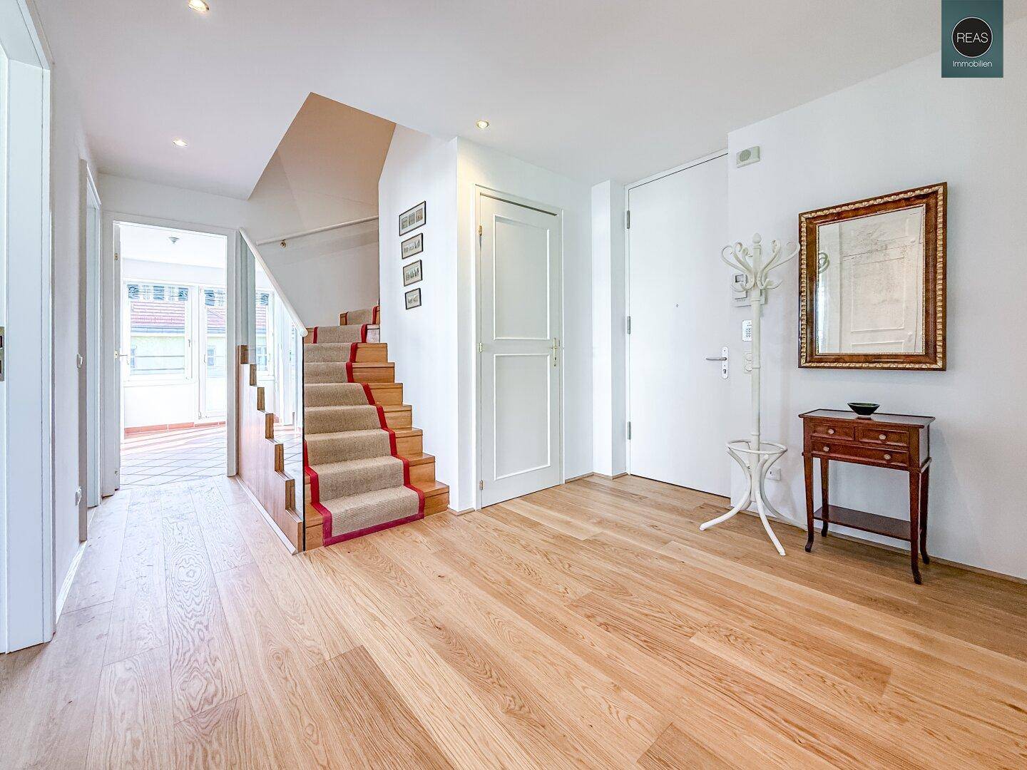 Geräumiger Eingangsbereich mit Holztreppe, Parkettboden und Garderobe.