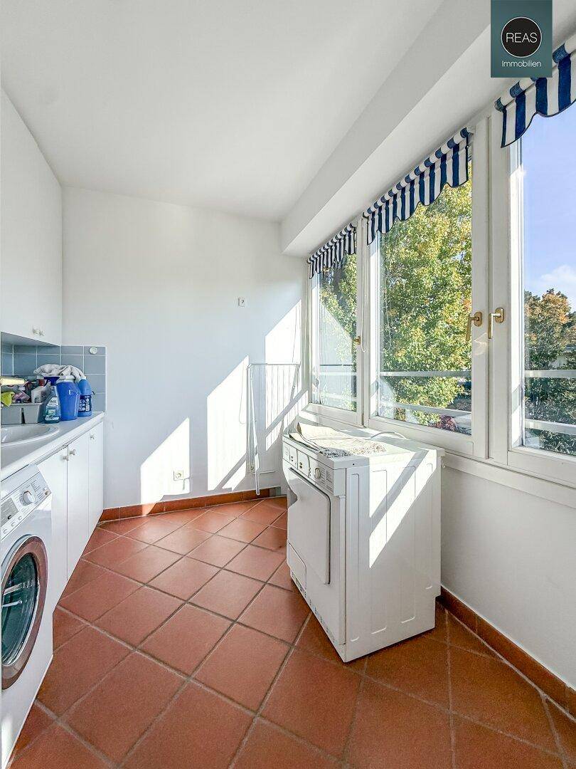 Praktischer Hauswirtschaftsraum mit Waschmaschine, Trockner und großen Fenstern für viel Tageslicht.