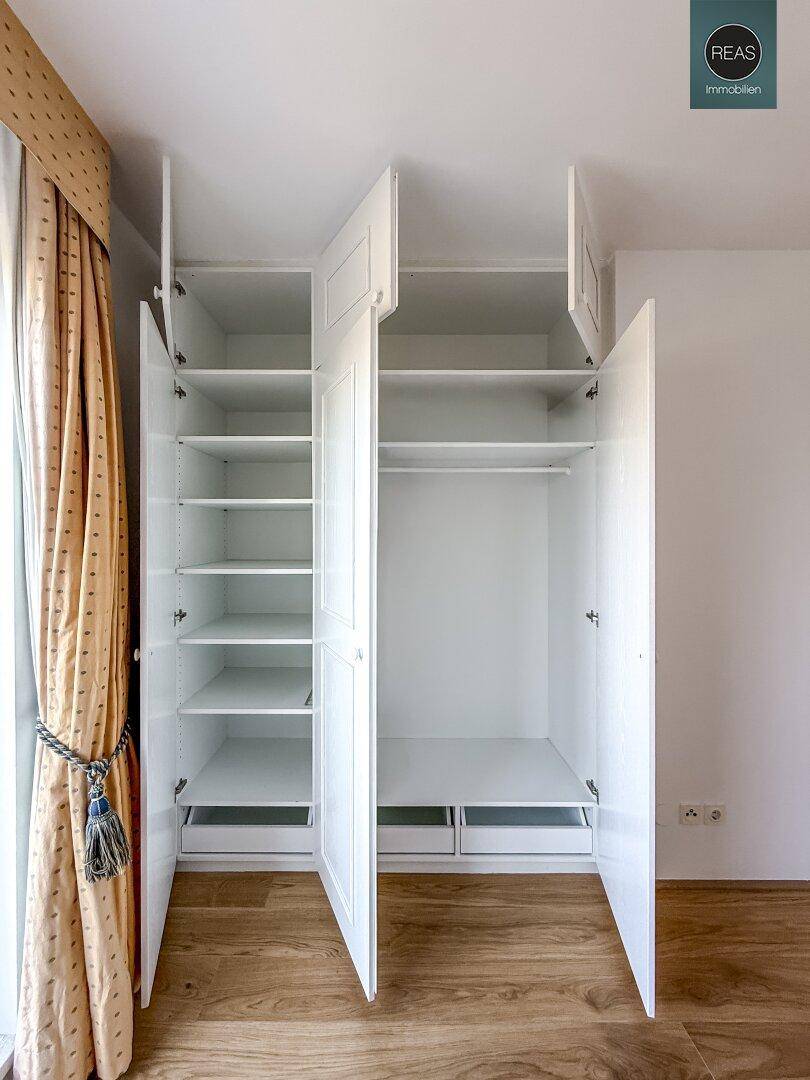Offene Einbauschränke im Schlafzimmer zeigen praktische Regale und Kleiderstangen.