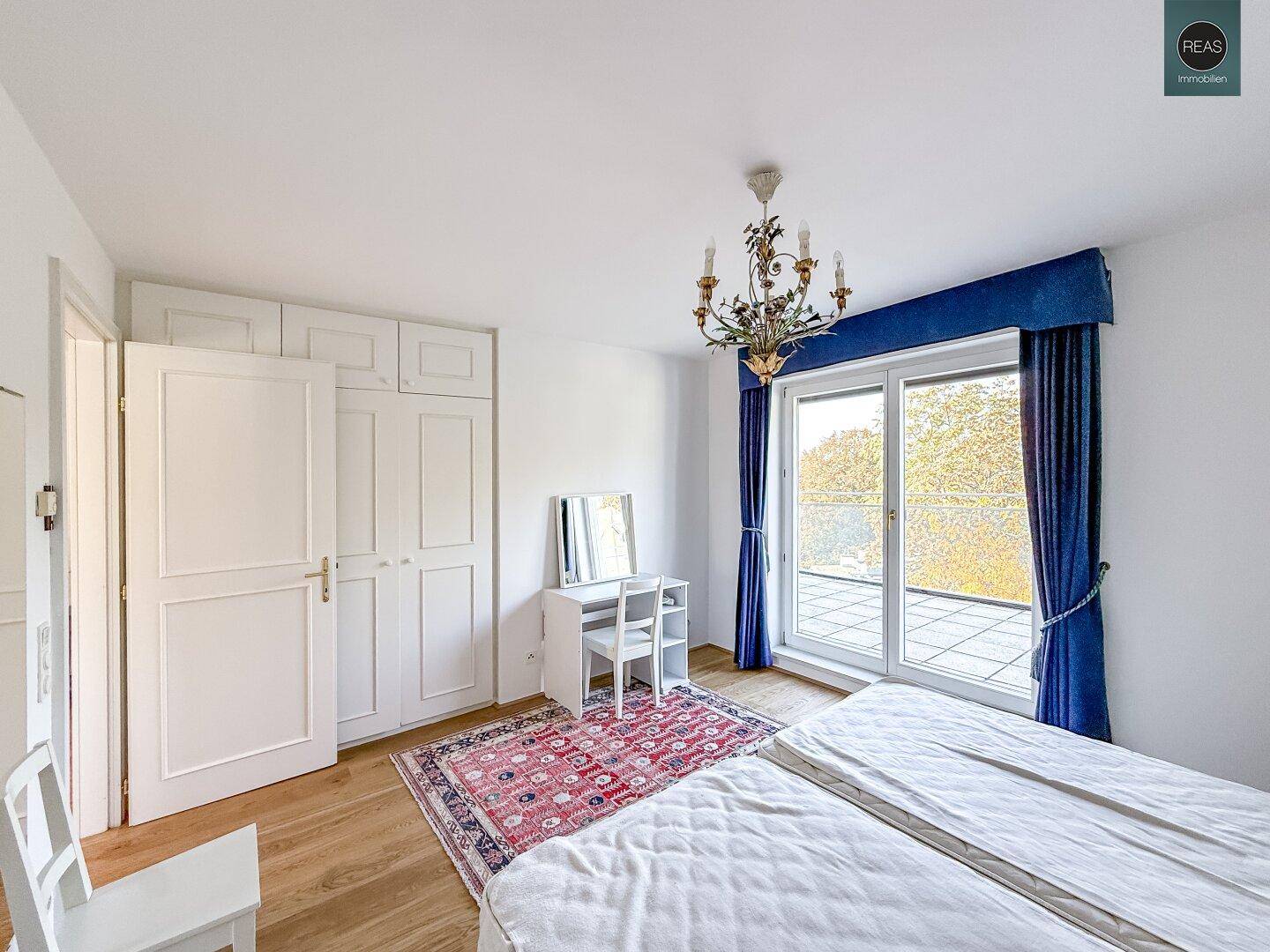 Schlafzimmer mit Einbauschränken, Parkettboden und Zugang zum Balkon.