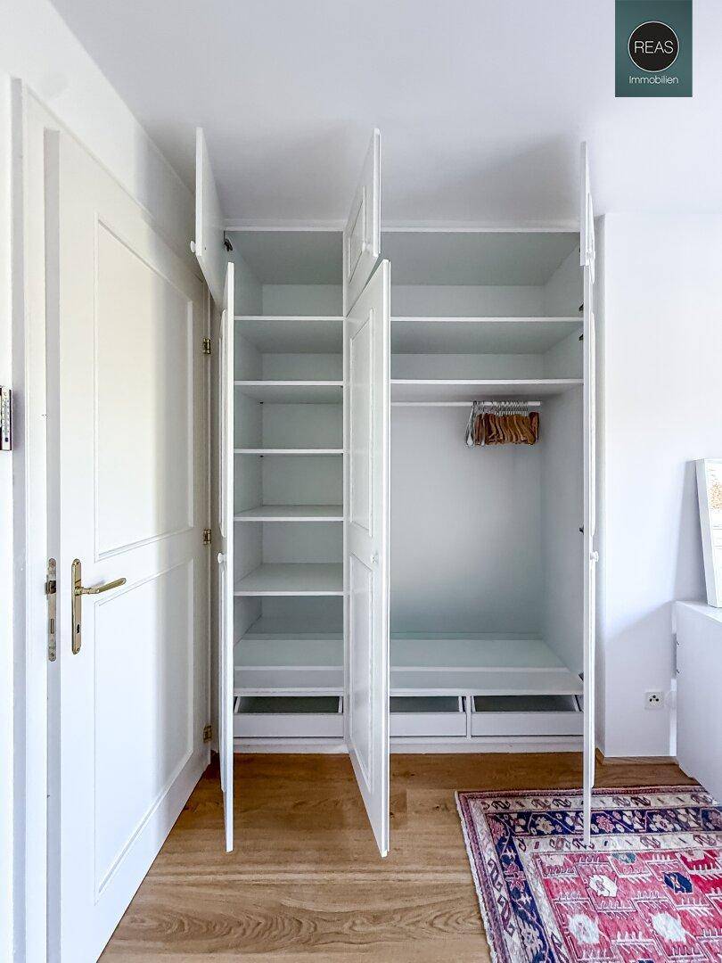 Offene Einbauschränke im Schlafzimmer zeigen praktische Regale und Kleiderstangen.