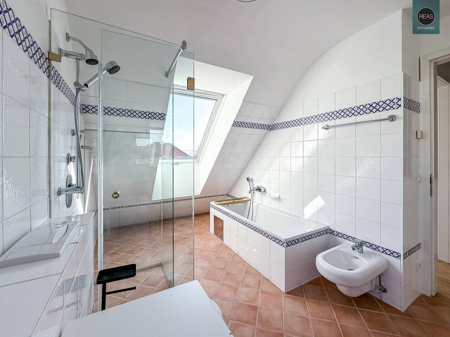 Helles Badezimmer im Dachgeschoss mit Dusche, Badewanne, Bidet und schrägen Wänden.