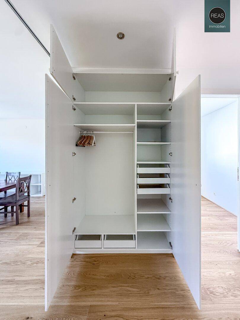 Geöffneter Einbauschrank mit viel Stauraum, Regalen und Schubladen im Flurbereich.