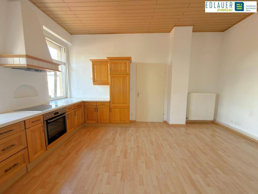 Geräumige Küche mit Holzschränken, Laminatboden und viel Platz für einen Essbereich.