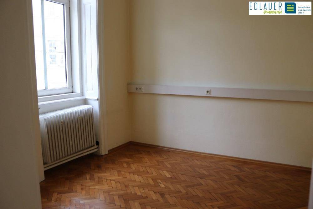 Kleineres Zimmer mit Fischgrätparkett und einem Fenster, das für natürliches Licht sorgt.