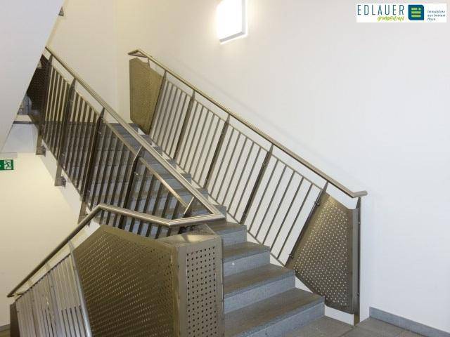 Moderne Treppe mit Metallgeländer und perforierten Paneelen, die ein industrielles Design aufweist.
