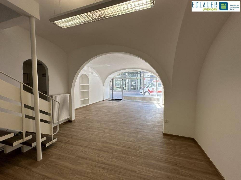 Blick vom Treppenbereich durch den offenen Raum zur großen Fensterfront, die viel Tageslicht hereinlässt.