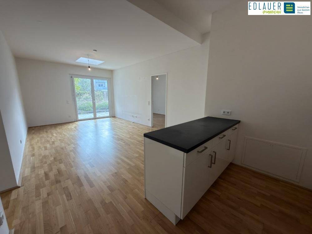 Geräumiger Wohnbereich mit Holzboden und Zugang zu einem Außenbereich, ideal für entspannte Stunden.