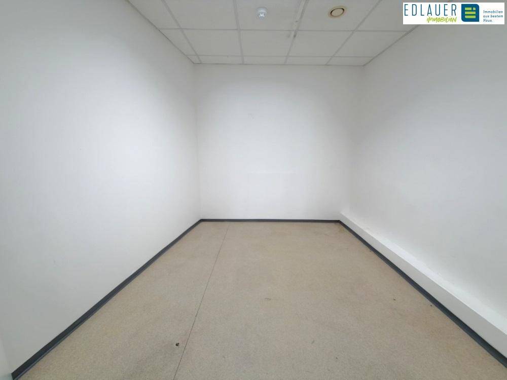 Kleiner, leerer Raum mit weißen Wänden, beigem Boden und einer Rasterdecke, ideal als Büro.
