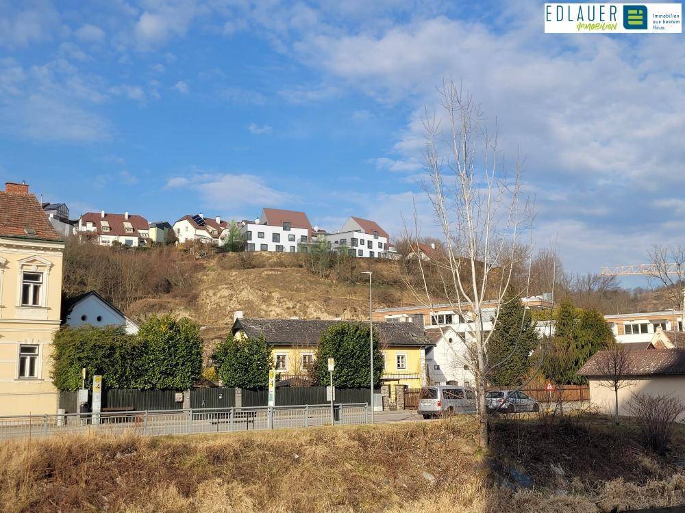 Blick auf eine Wohnsiedlung am Hang mit verschiedenen Häusern unter blauem Himmel.