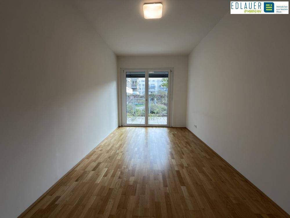 Lichtdurchfluteter Raum mit Holzboden und großen Fenstern, bietet eine angenehme Atmosphäre.
