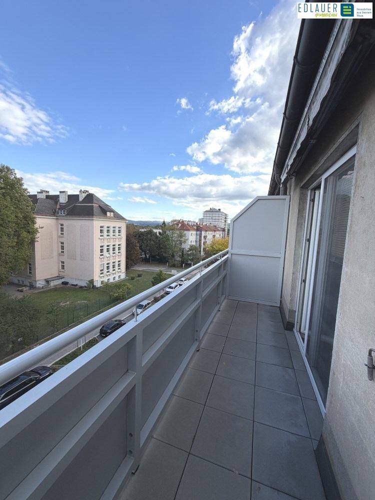 Geräumiger Balkon mit Fliesen und weitem Blick über die Stadt und grüne Bereiche.