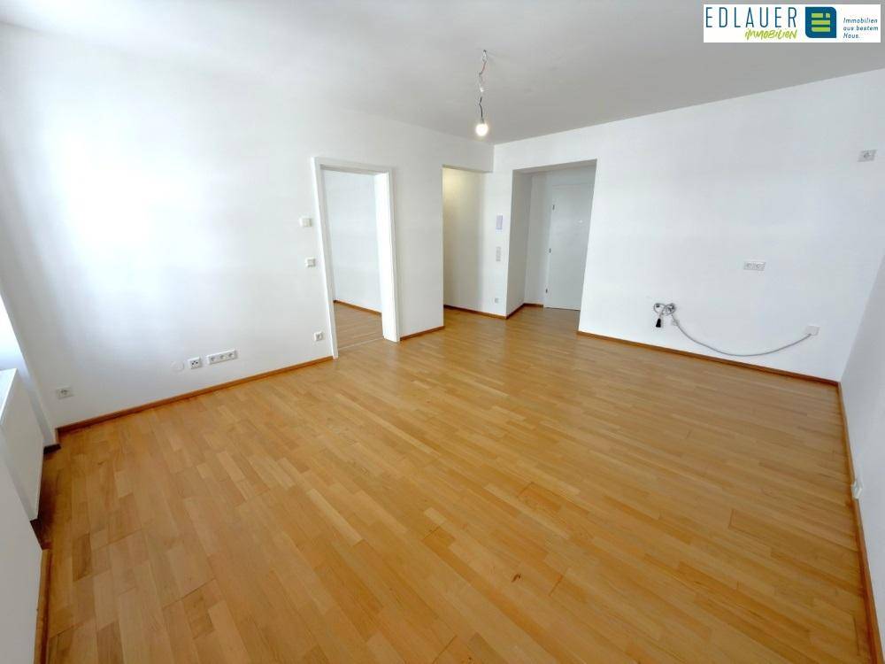 Geräumiges Wohnzimmer mit Parkettboden und mehreren Türöffnungen, bietet vielseitige Nutzungsmöglichkeiten.