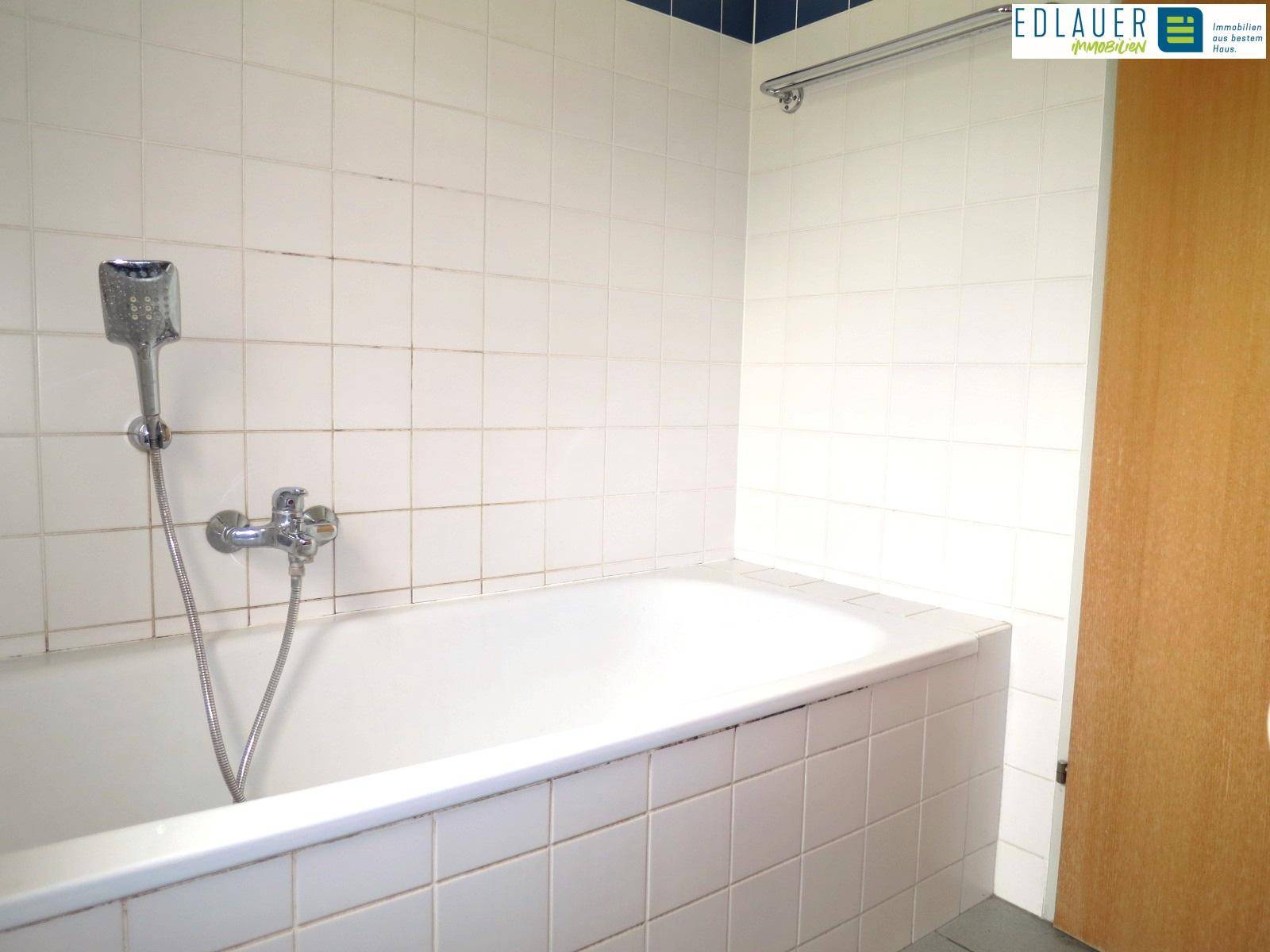 Badezimmer mit Badewanne und weißen Fliesen, bietet Raum für Entspannung.