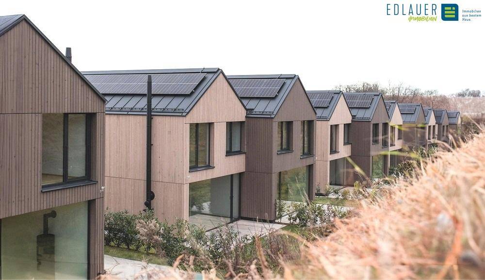 Eine Reihe von modernen Reihenhäusern mit Holzfassaden und großen Glasfronten.