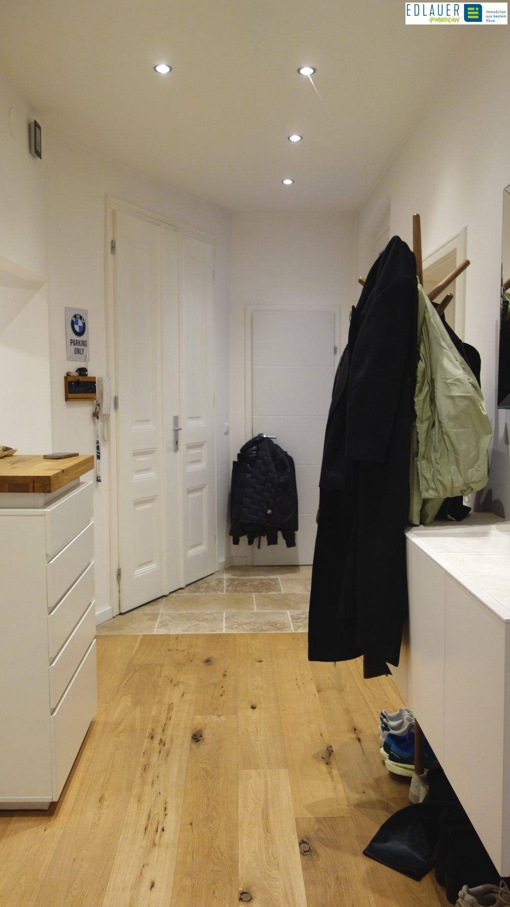 Heller Flur mit Holzboden, Einbaustrahlern und Garderobe.