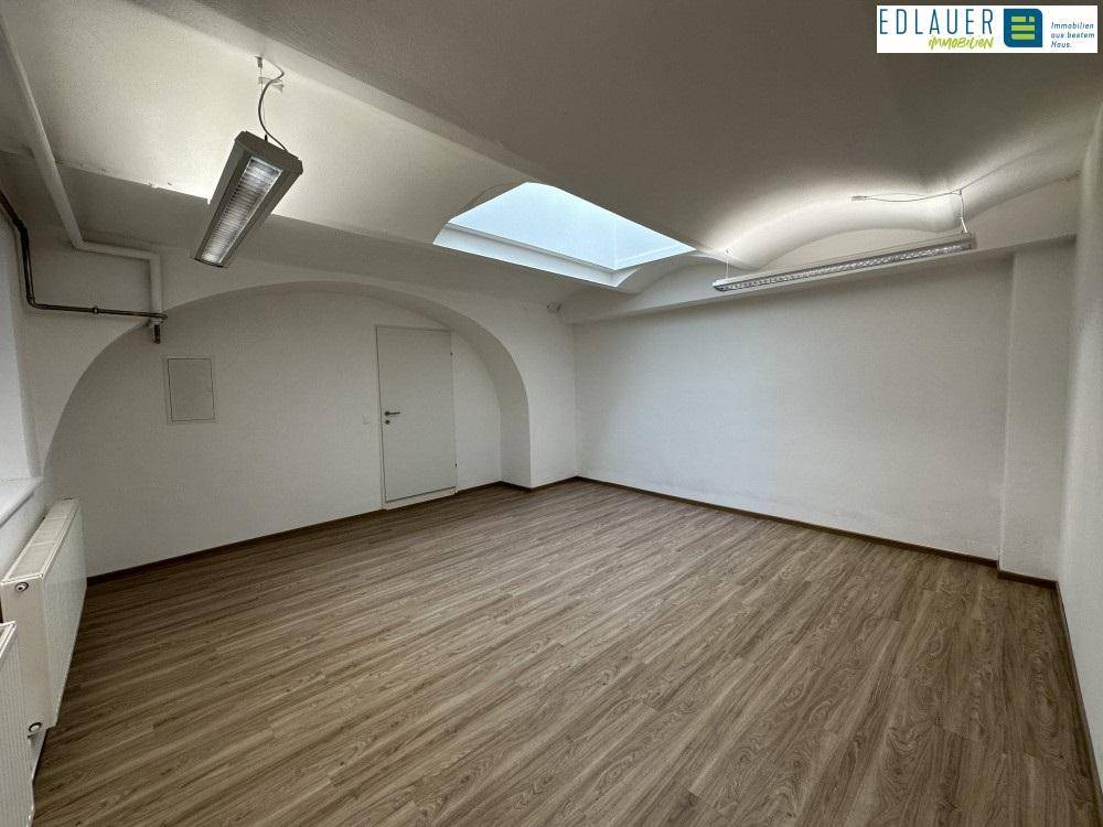 Weiterer Blick in den hellen Raum mit Laminatboden, Oberlicht und Deckenleuchten, der vielseitig nutzbar ist.