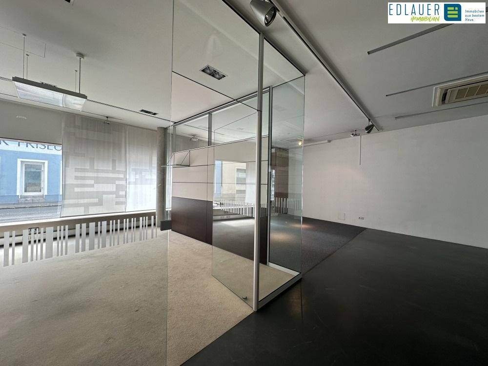 Heller Büroraum mit Teppichboden, Glaswänden und Blick auf die Stadt, der eine inspirierende Arbeitsumgebung schafft.