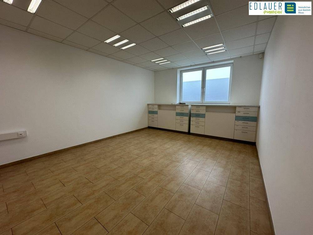 Büroraum mit integrierten Schränken, Fliesenboden und Fenster, bietet praktischen Stauraum und Arbeitsfläche.