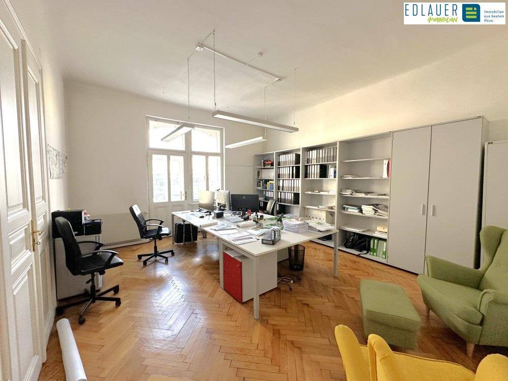 Geräumiges Büro mit Fischgrätparkett, großen Fenstern und moderner Büroeinrichtung, ideal für produktives Arbeiten.