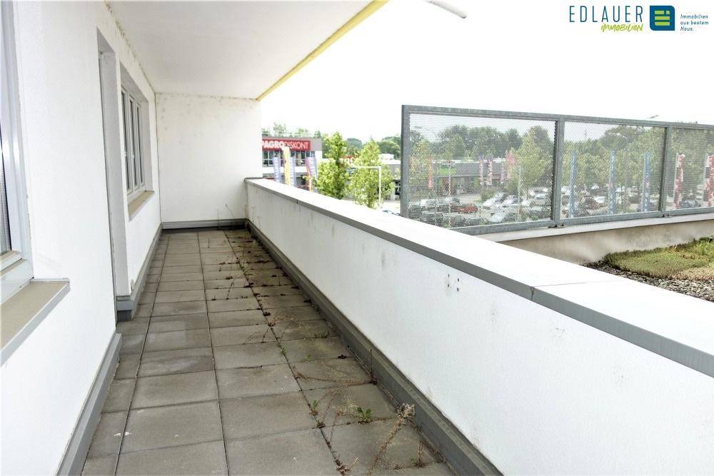 Langer Balkon mit Fliesenboden und Metallgeländer, bietet Ausblick auf die Umgebung.