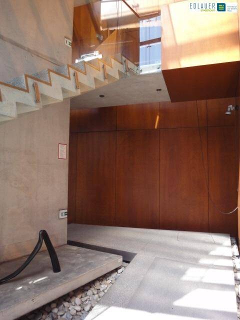 Heller, moderner Eingangsbereich mit Holzpaneelen, Steinfliesen und einer offenen Treppe, die nach oben führt.