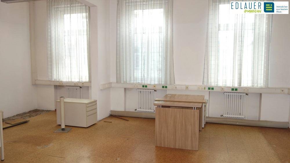 Heller Büroraum mit drei großen Fenstern, Heizkörpern und einfacher Einrichtung, bereit zur individuellen Gestaltung.