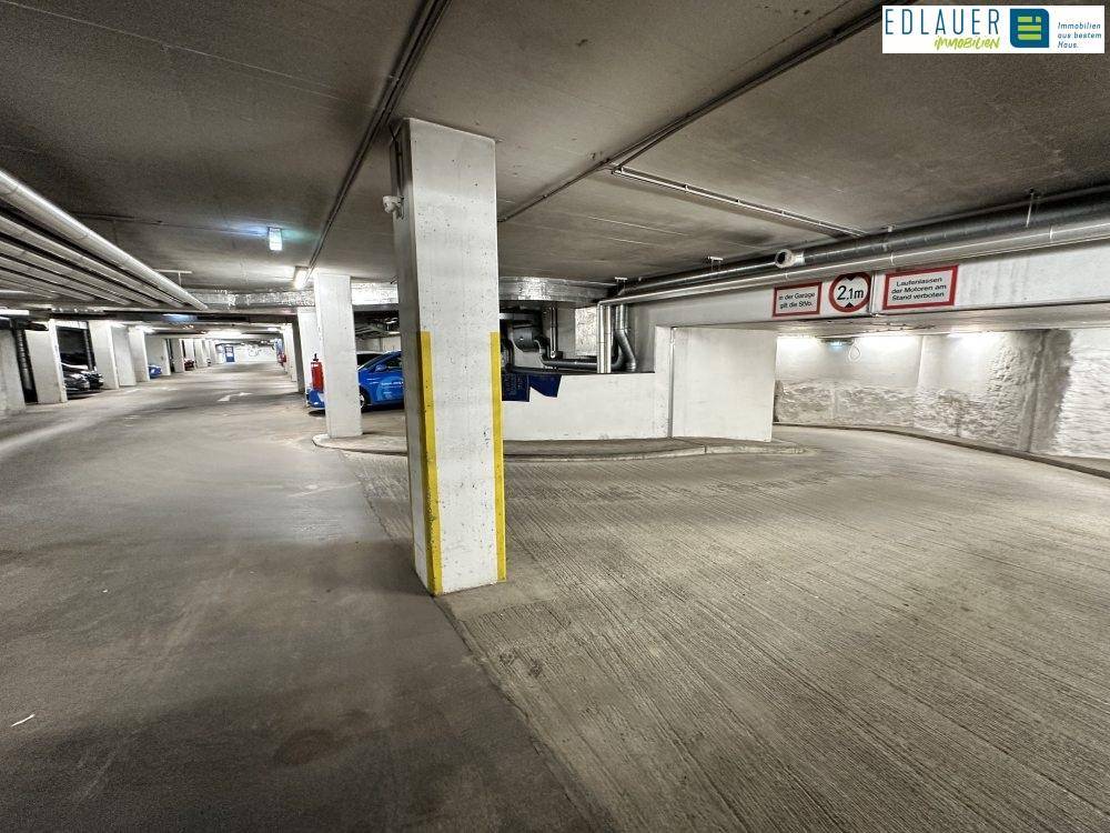 Zufahrtsrampe in der Tiefgarage mit Höhenbegrenzung und robusten Betonwänden.