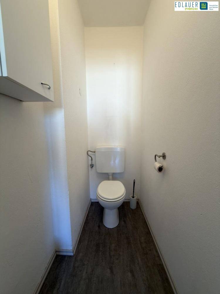 Separates WC mit Toilette und schlichten weißen Wänden.