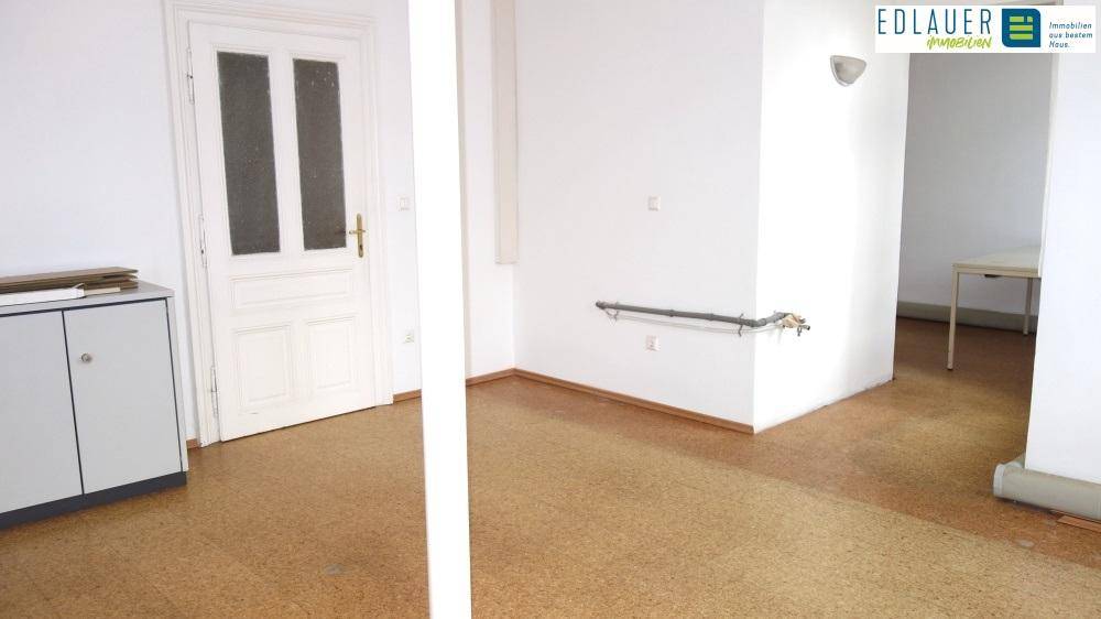 Heller Flur mit Linoleumboden und einer weißen Tür, führt zu weiteren Räumen im Gebäude.