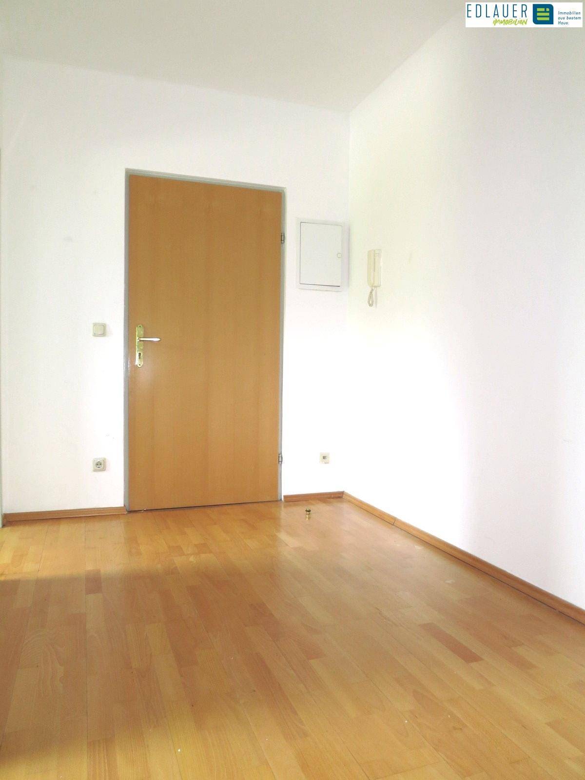 Heller Raum mit Holztür und Parkettboden, geeignet als Arbeits- oder Gästezimmer.