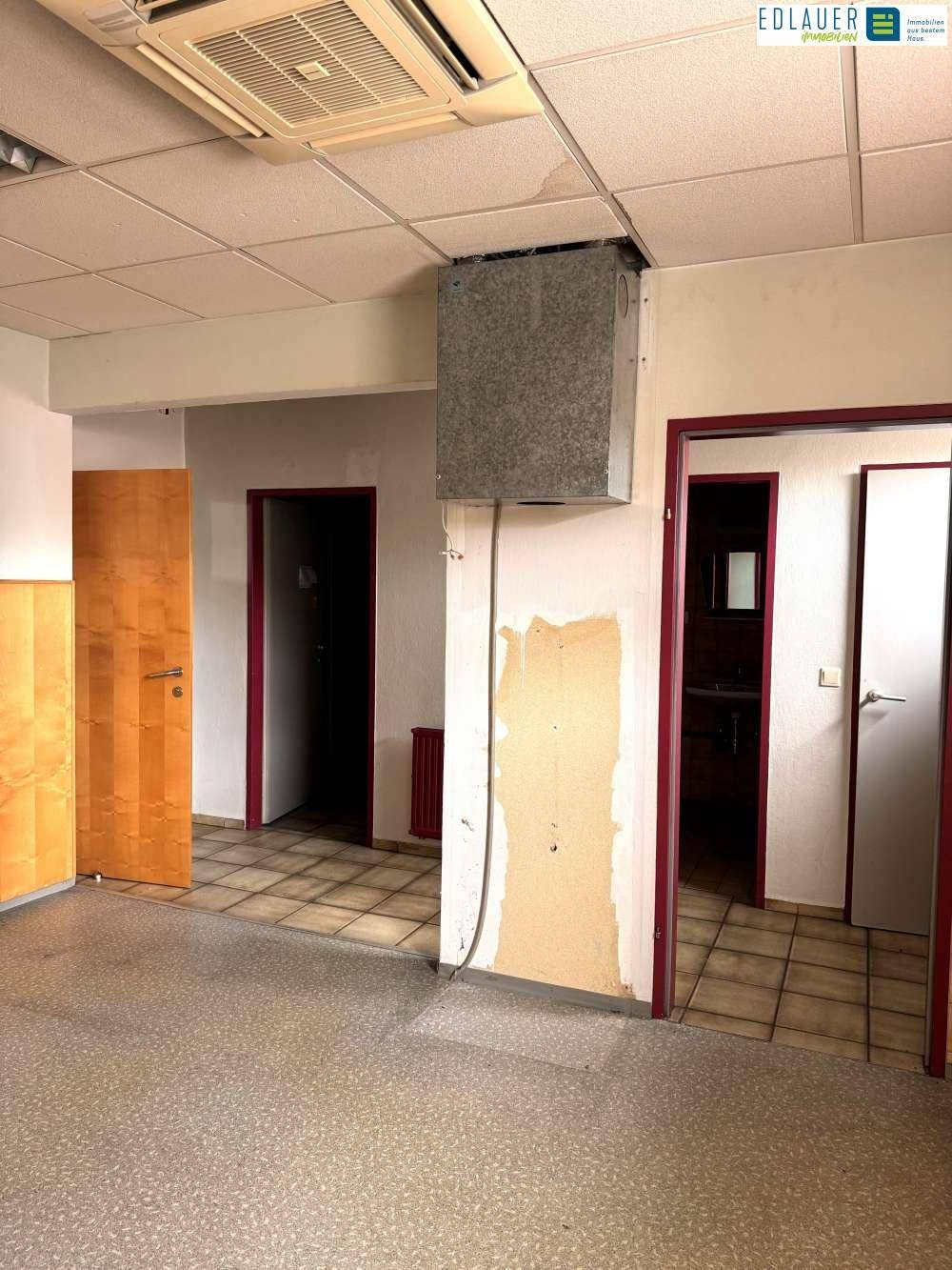 Raum mit Fliesenboden, mehreren Türen und sichtbaren Installationen an der Decke.