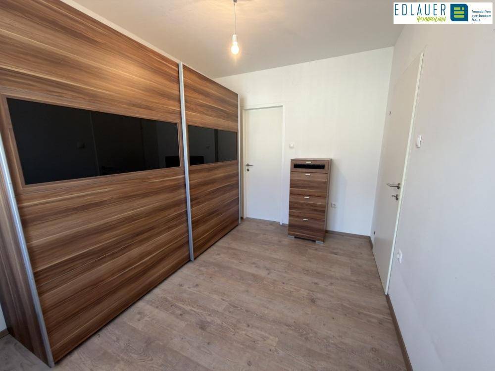 Schlafzimmer mit großem Holzschrank und Laminatboden, bietet viel Stauraum.