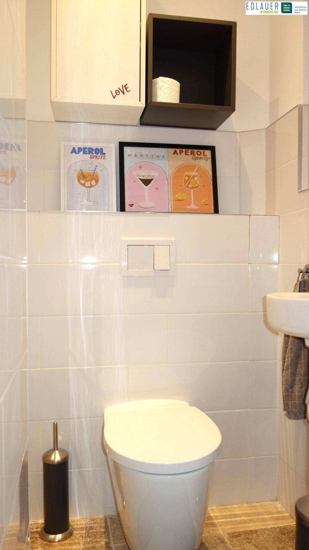 Kleines Gäste-WC mit Wand-WC, Waschbecken und modernen Bildern.