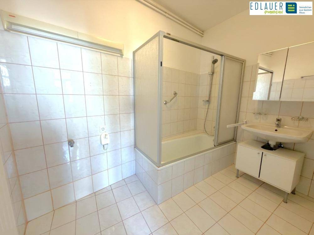 Gefliestes Badezimmer mit Badewanne, Duschabtrennung und Einzelwaschbecken.