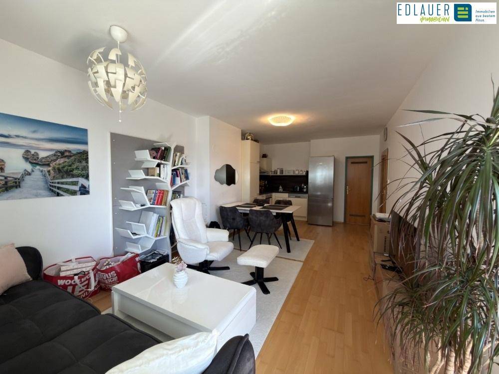 Geräumiger Wohnbereich mit Sofa, Sessel und Blick auf den Essbereich und die Küche.