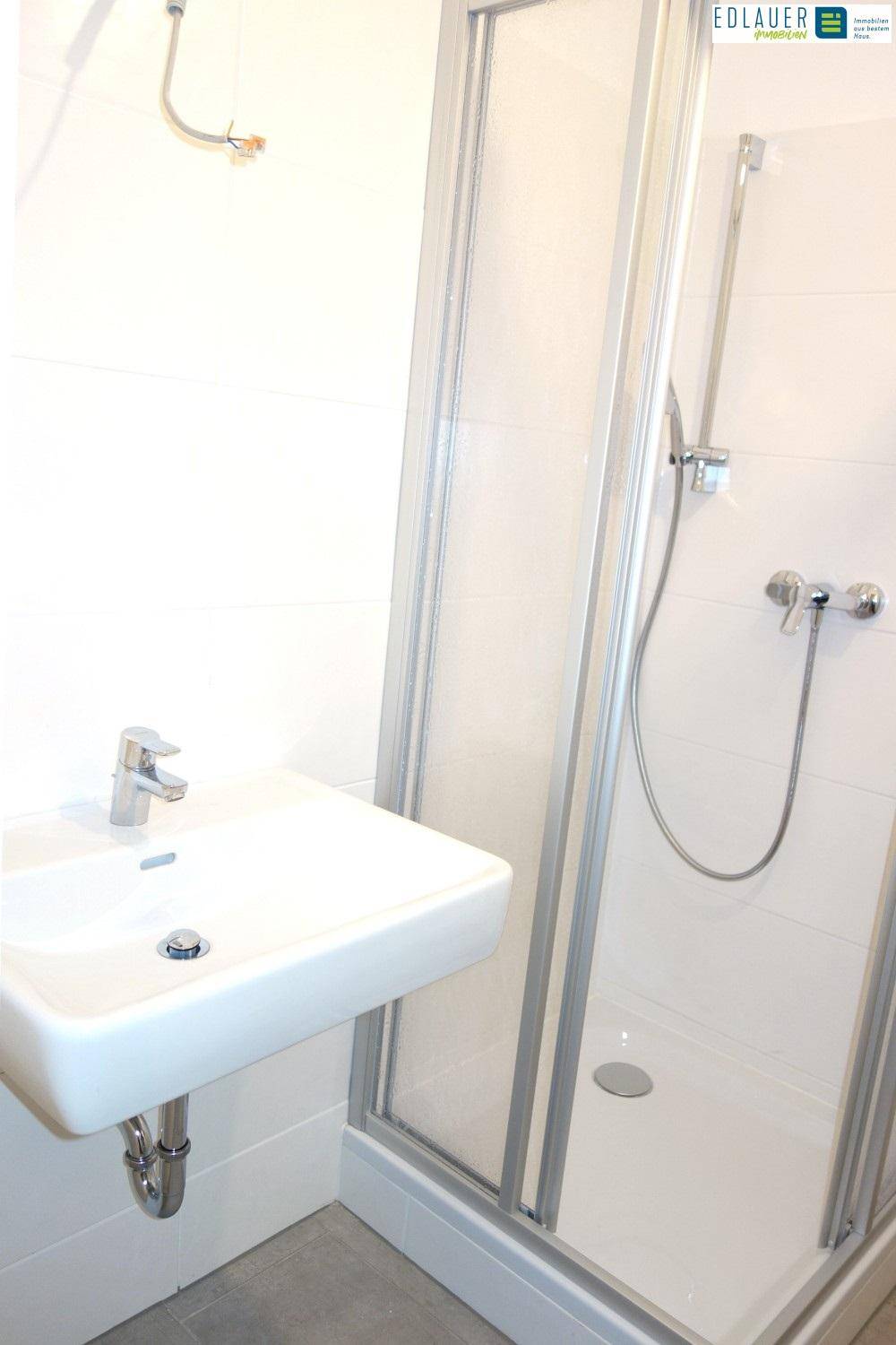Modernes Badezimmer mit Duschkabine, Waschbecken und weißen Wandfliesen.