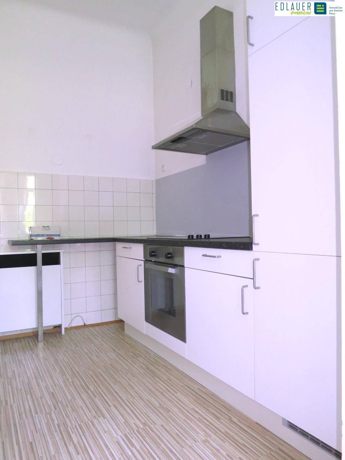 Funktionale Küche mit weißen Schränken, integriertem Backofen und Dunstabzugshaube.