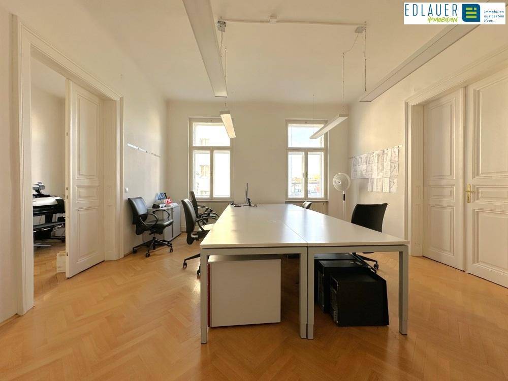 Helles Büro mit Holzboden, großen Fenstern und viel Tageslicht, das eine angenehme Arbeitsatmosphäre schafft.