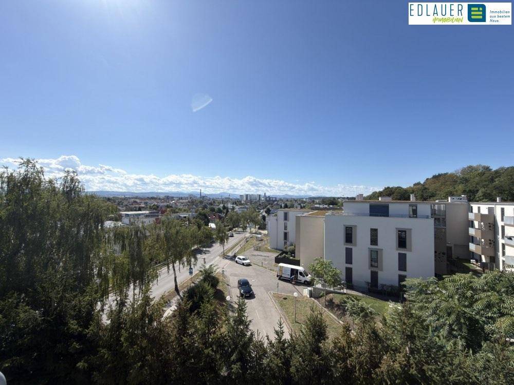 Weitläufiger Blick über die Stadt und die umliegende Landschaft unter blauem Himmel.
