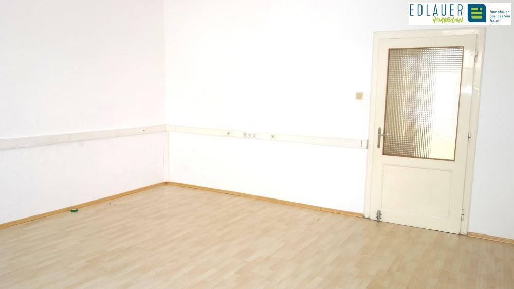 Leerer Raum mit einer Tür und hellem Laminatboden, ideal für verschiedene Nutzungsmöglichkeiten.