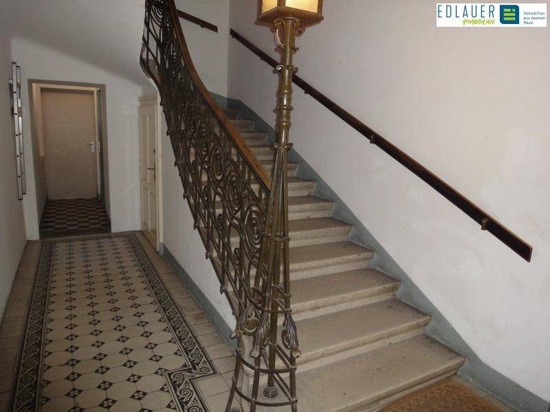 Historisches Treppenhaus mit kunstvollem schmiedeeisernem Geländer und gemusterten Fliesenböden.