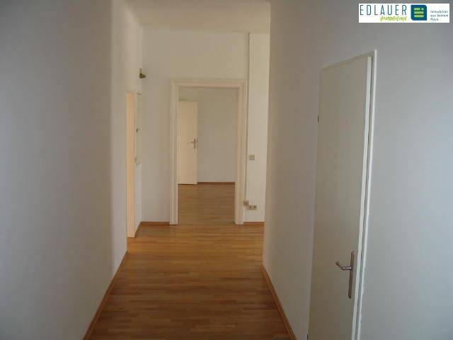 Langer Flur mit Holzboden und mehreren Türen, der verschiedene Räume der Wohnung miteinander verbindet und eine klare Struktur bietet.
