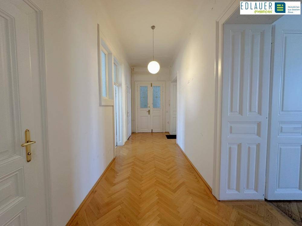 Langer Flur mit Fischgrätparkett und weißen Türen, der zu verschiedenen Räumen führt und viel Charme besitzt.