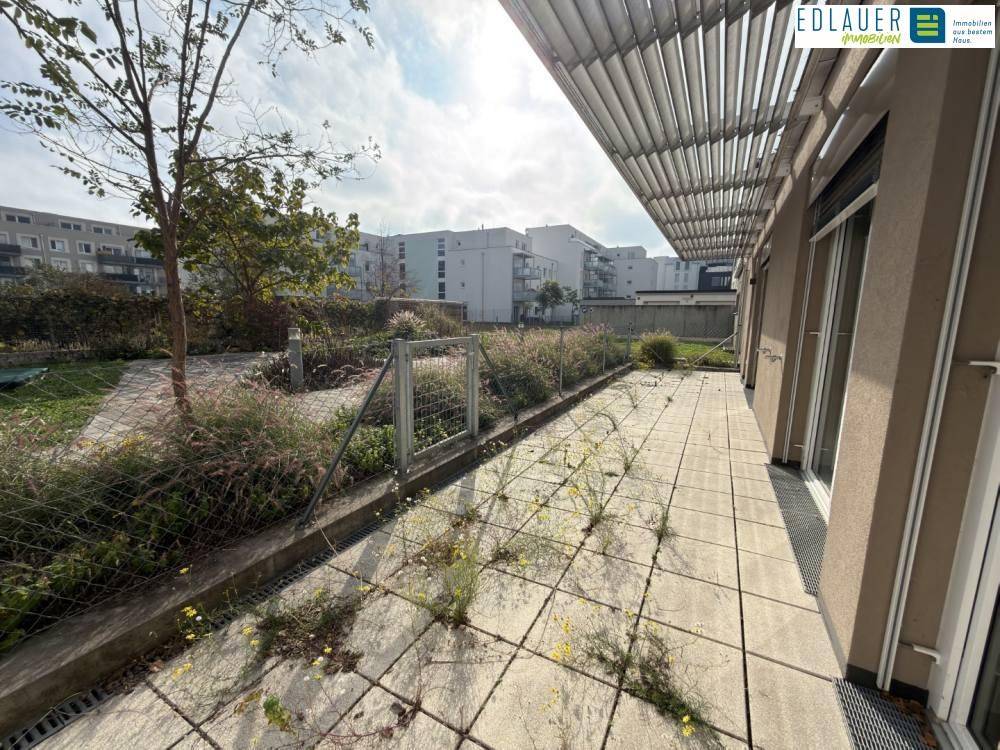 Geräumige Terrasse mit Plattenboden und angrenzendem Grünbereich, ideal für Entspannung im Freien.