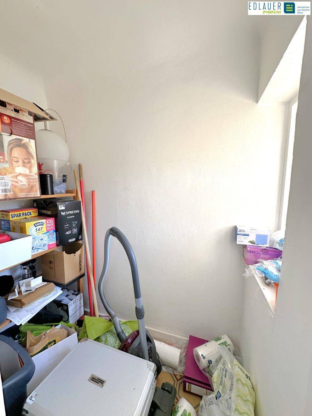 Kleiner Abstellraum mit Fenster, gefüllt mit verschiedenen Gegenständen und Haushaltsgeräten für zusätzlichen Stauraum.