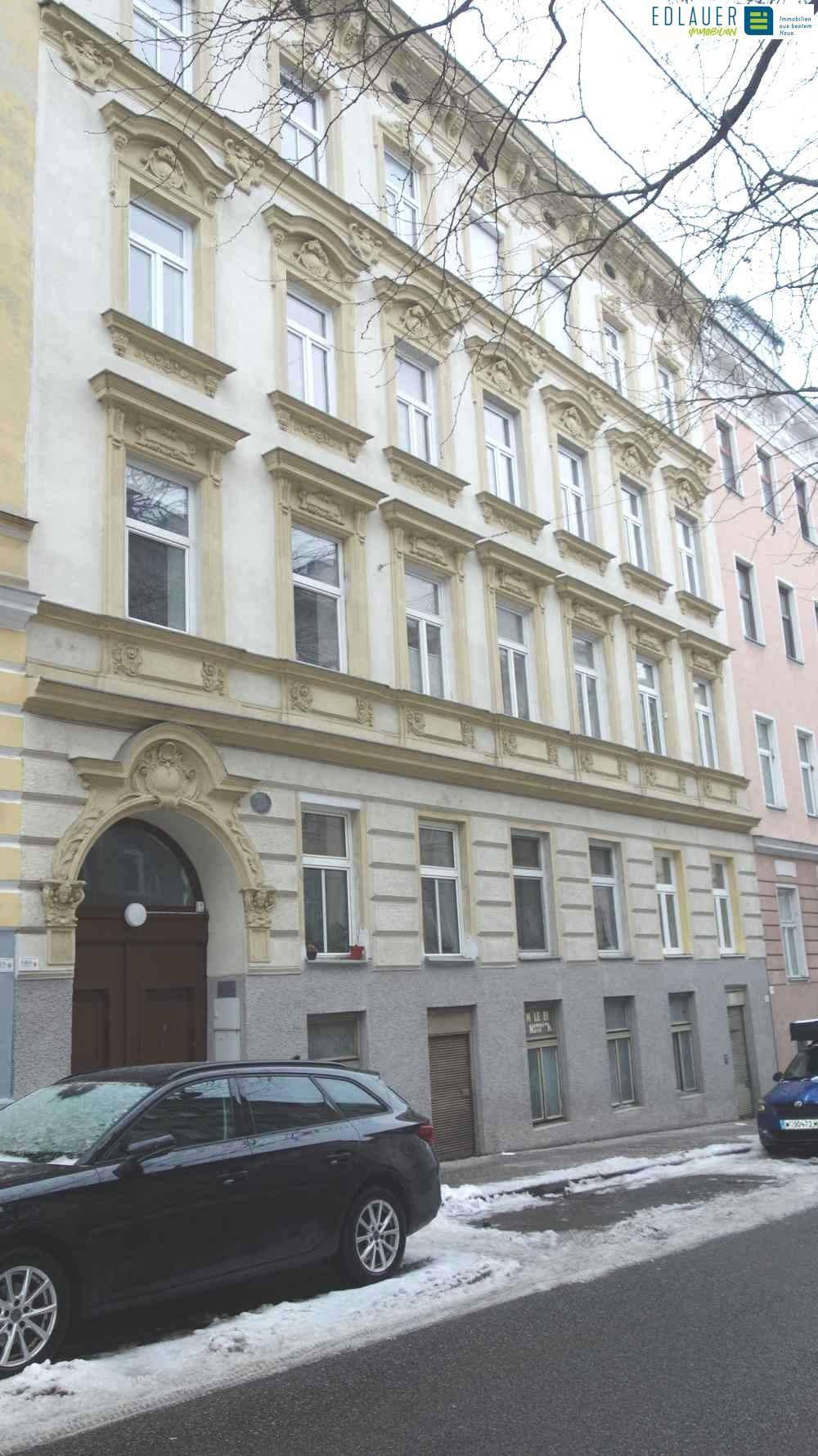 Detailansicht der historischen Altbaufassade mit Stuckelementen und Fenstern.