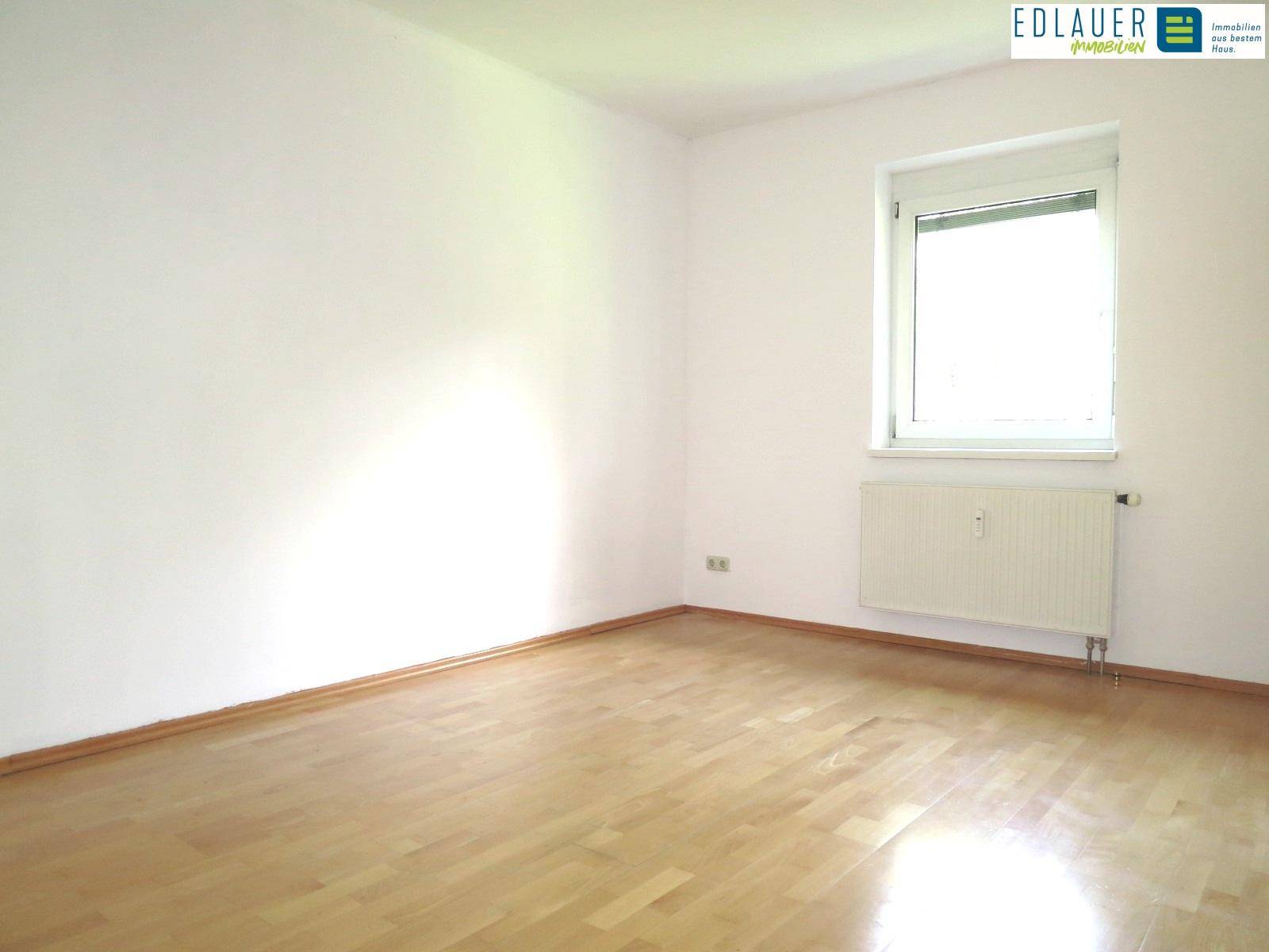 Geräumiges Zimmer mit Parkettboden und Fenster, ideal als Kinder- oder Gästezimmer.